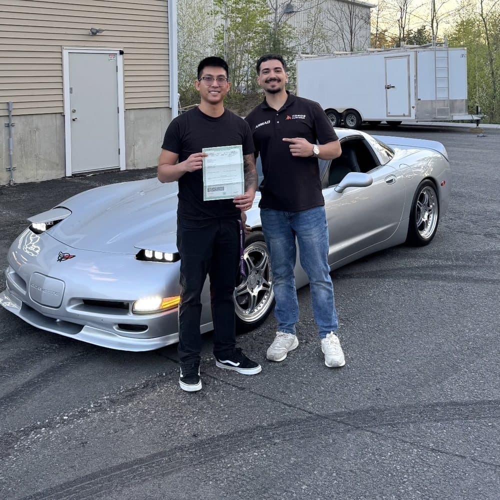 Two people with a silver C5 Corvette outside the shop