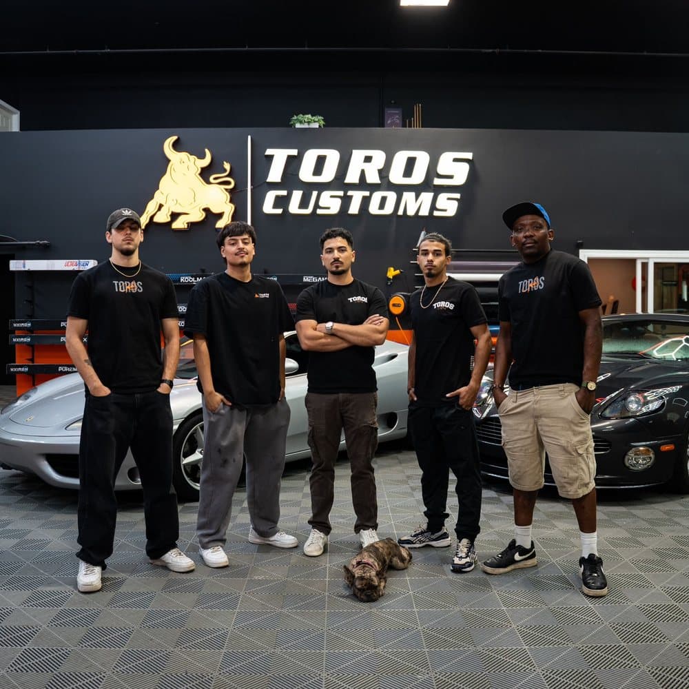 The Toros Customs team in front of the shop's sign